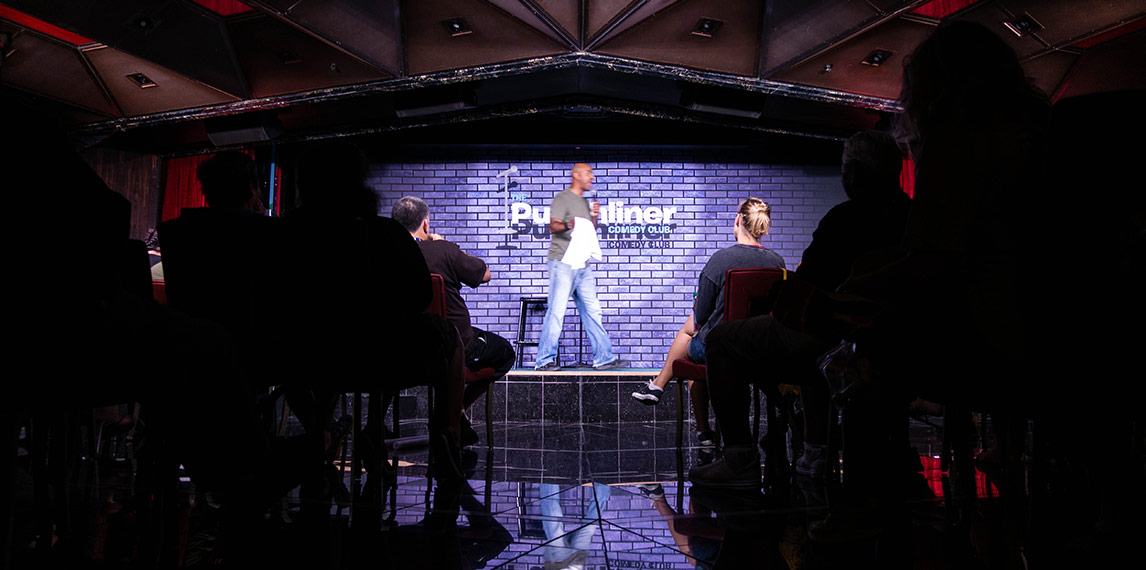 Comedian on stage performing at Punchliner comedy club.